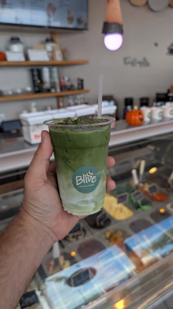 Iced matcha latte in a Blive cup held over the gelato case