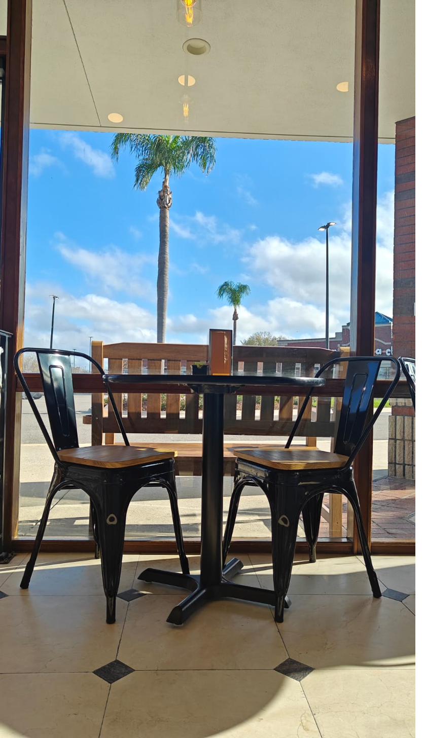 Two chairs at a table by the window with palm trees outside